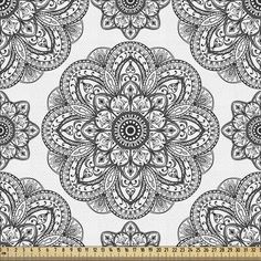 a white and black floral print fabric with an intricate flower design on the center, in front of a ruler