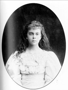 an old black and white photo of a young woman in a dress with long hair