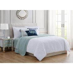 a bed with blue and white comforters in a bedroom next to a table lamp