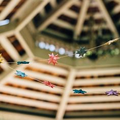 colorful paper stars are hanging from a string in the middle of an indoor space that looks like a building