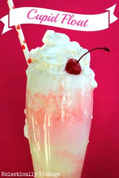 a tall glass with whipped cream and a cherry on the top, sitting in front of a pink background