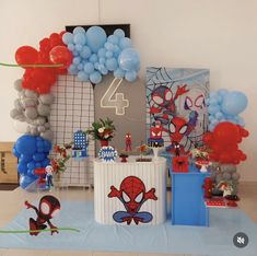 a birthday party with balloons, decorations and spider - man cake on the table in front of it