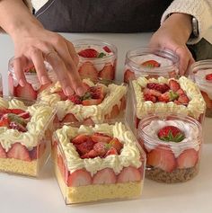 a person placing strawberries on top of some desserts