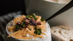 a close up of a bowl of food with bread and cheese on the side,