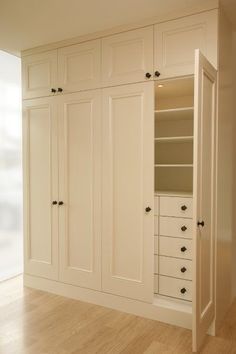 an empty room with white cupboards and drawers in the center, on hard wood flooring