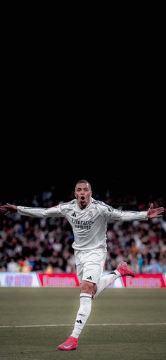 a soccer player in action on the field with his arms out and feet spread wide