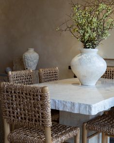 a white vase sitting on top of a table next to wicker chairs