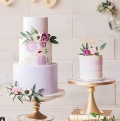 three wedding cakes sitting on top of each other in front of a white brick wall