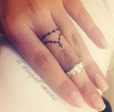 a person's hand with a ring on it and a cross tattoo on the middle finger