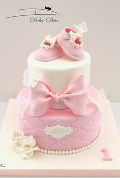 a pink cake with baby shoes on top