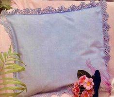 a blue pillow sitting on top of a bed next to a plant