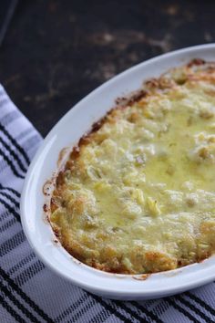 a casserole dish with cheese and sauce in it on a checkered table cloth