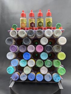 an artistic display made out of bottles and paintbrushes on a black stand with silver background