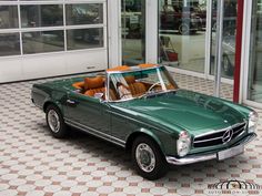 a green convertible car parked in front of a building with lots of windows and doors