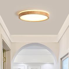 a hallway with white walls and an arched doorway leading to another room that has a light fixture on the ceiling