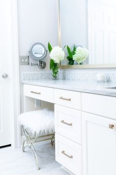 a white bathroom with marble counter tops and drawers