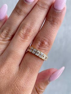 a woman's hand with a gold ring on it and pink nail polishes