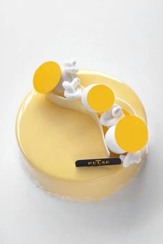 there is a yellow cake with white frosting and three orange circles on top that are shaped like toothbrushes