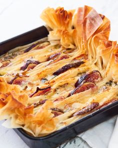 a casserole dish with meat and cheese in it on a white tablecloth