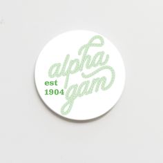 a white button with green lettering that says,'appla gam est 1940 '