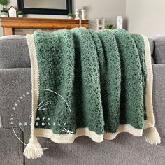 a green and white blanket sitting on top of a gray couch next to a mirror