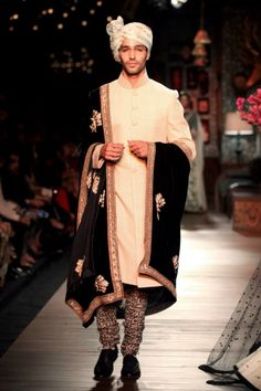 a man walking down a runway wearing a turban