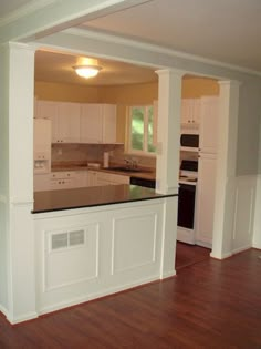 an empty kitchen with wood floors and white cabinets