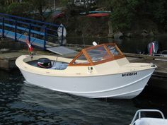 a small white boat in the water near a dock