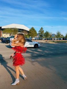 a woman in a red dress is walking down the street