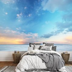 a bed with pillows and blankets on top of it in front of a wall mural