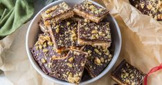 a bowl filled with chocolate and nuts on top of parchment paper next to a red ribbon