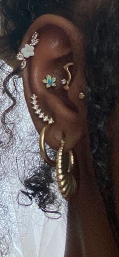 a close up of a person with ear piercings on their ears and wearing gold rings