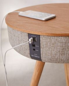 an electronic device is plugged into the side of a round table with wooden legs