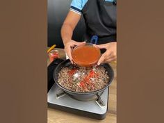 a man in an apron is pouring sauce into a pan