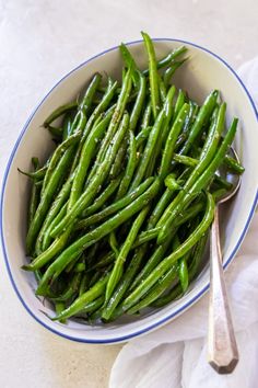 a bowl filled with green beans on top of a table