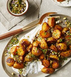 a plate full of fried potatoes with sour cream and pistachio sprinkles