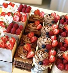 there are many cakes and strawberries on the table with chocolate frosting in them