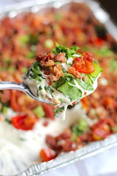 a close up of a spoonful of food on top of a casserole dish