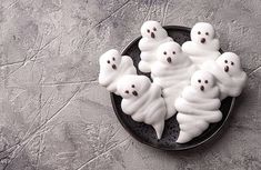 some white ghost cookies on a black plate