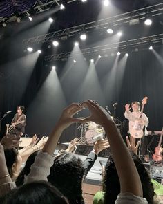 a group of people standing on top of a stage with their hands in the air