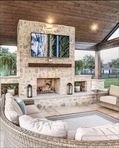 an outdoor living room with stone fireplace and seating