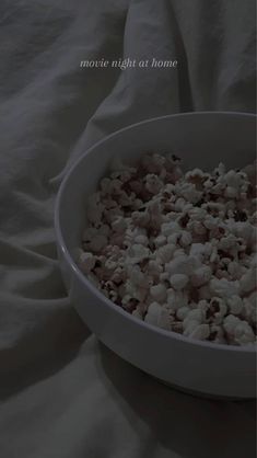 a white bowl filled with popcorn on top of a bed