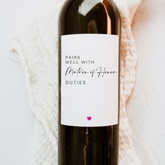 a bottle of wine sitting on top of a white blanket next to a pink heart