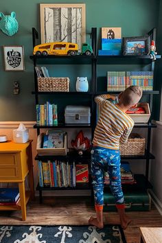 a young boy standing in front of a bookshelf with toys on the shelves