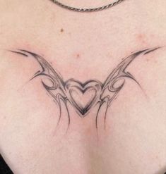 a woman's chest with an intricate heart and wings tattoo design on her back