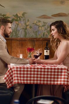 a man and woman sitting at a table with wine glasses