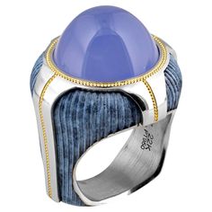 One of a Kind Blue Buddha Chalcedony Ring by Zoltan David is a masterpiece of unique design and exceptional craftsmanship. This exquisite ring features a striking blue chalcedony set in a beautifully crafted frame of patented precious metal. The use of blue chalcedony gives the piece a tranquil and mystical aura and showcases Zoltan David’s skill in selecting and enhancing fine gemstones. The intricate metalwork around the stone is a testament to David's innovative techniques, making this ring a truly distinctive piece in the world of luxury jewelry. It is expertly crafted in bronze and platinum, featuring a 24K gold-shaped inlay and a stunning 16.96-carat Chalcedony Cabochon center. Zoltan David is an award-winning jewelry designer known for his innovative use of precious metals and gemst Chalcedony Jewelry, Blue Buddha, Chrysocolla Jewelry, Platinum Rings, Award Winning Jewelry, Chalcedony Ring, Blue Ring, Platinum Diamond Rings, Diamond Fashion Rings