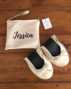 a pair of white shoes sitting on top of a wooden floor next to a bag