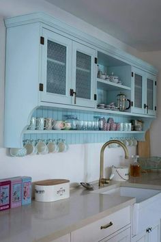 a kitchen with blue cabinets and dishes on the counter top in front of a sink