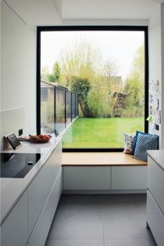 a kitchen with an open window overlooking a yard and trees in the backround